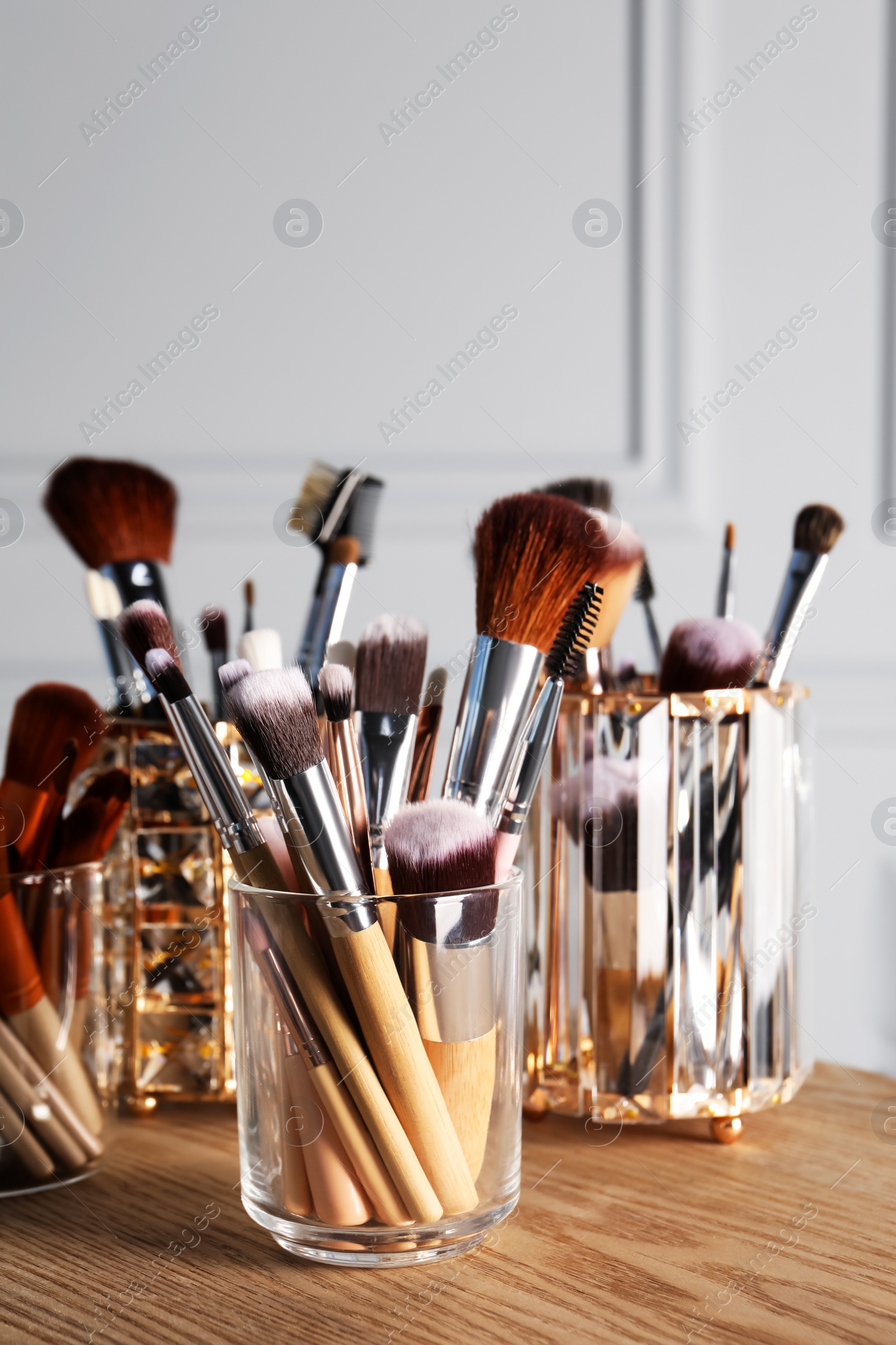 Photo of Set of professional makeup brushes on wooden table