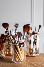 Photo of Set of professional makeup brushes on wooden table