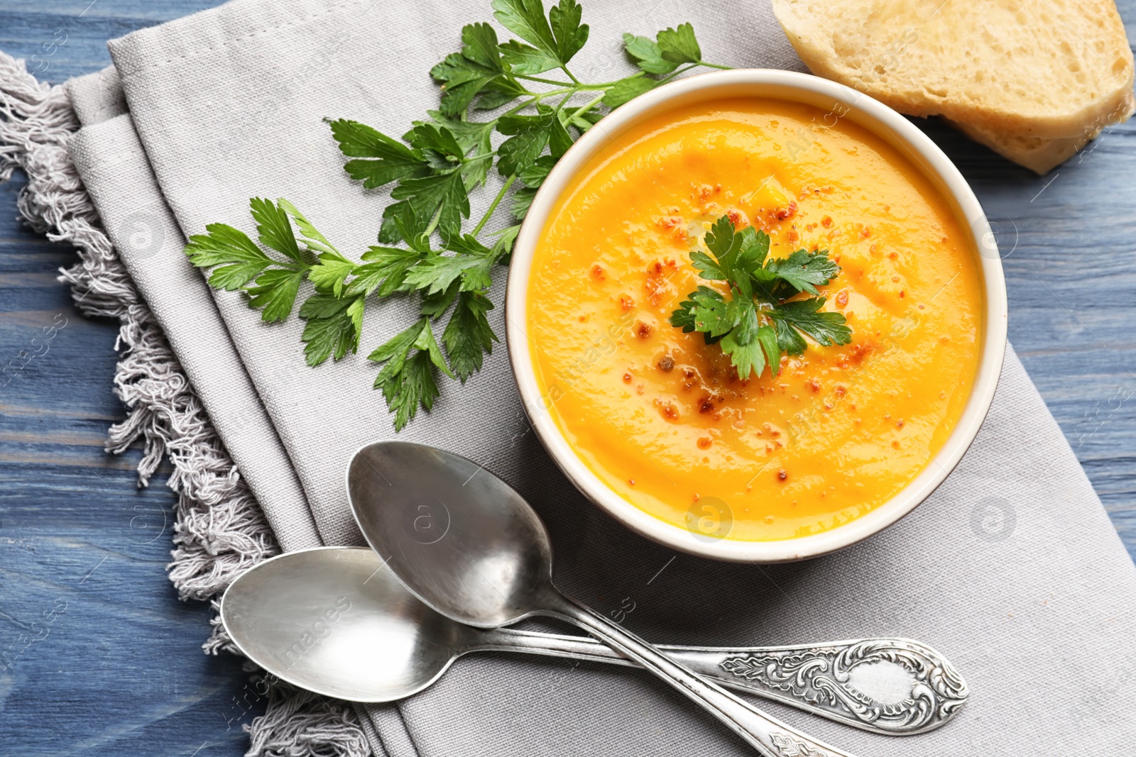 Photo of Flat lay composition with delicious pumpkin cream soup in bowl on wooden background