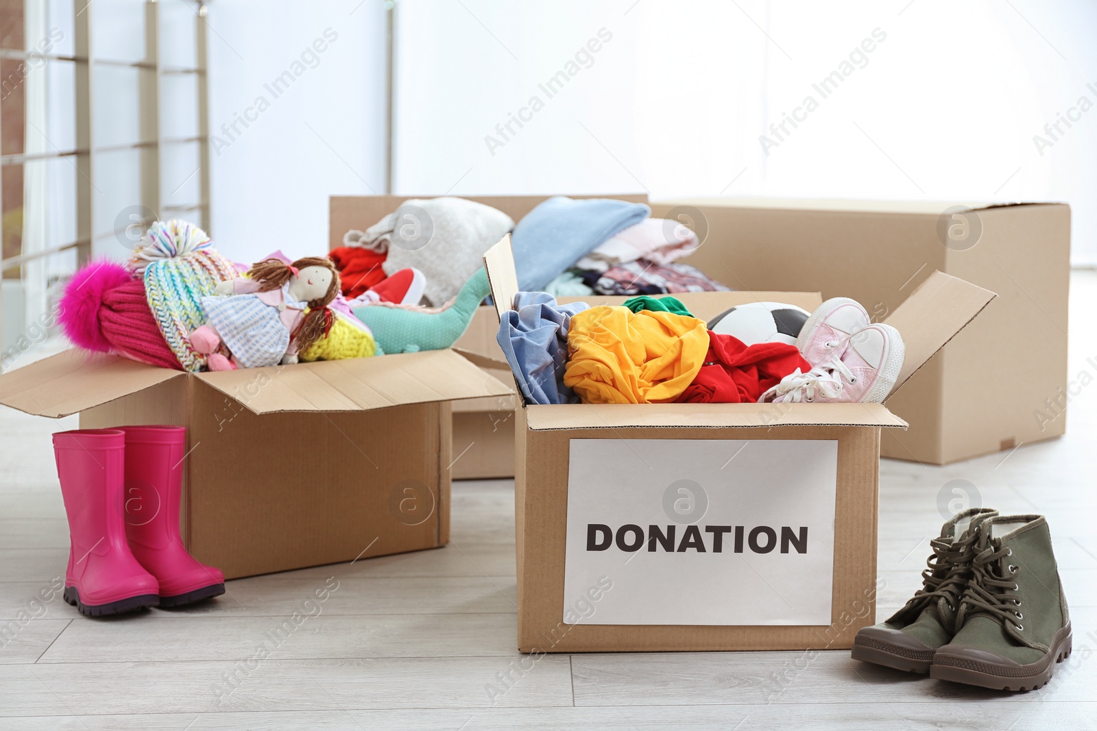 Photo of Carton boxes with donations on floor indoors