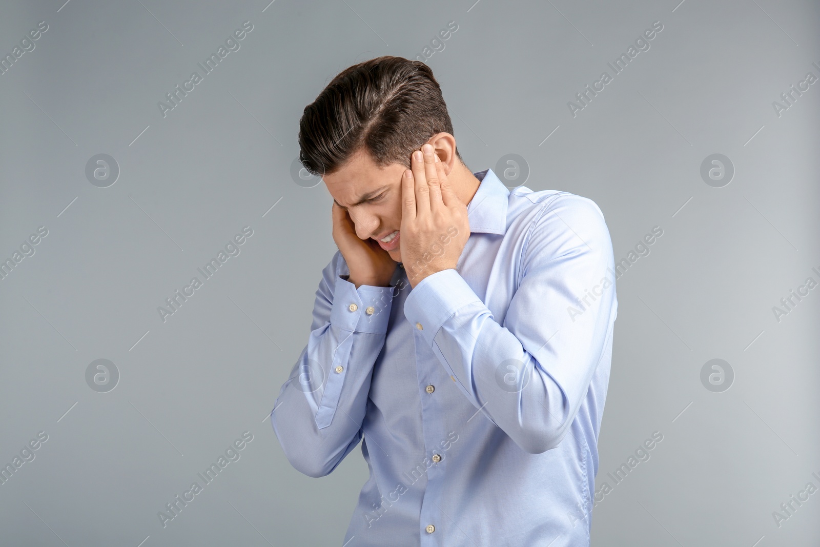 Photo of Young man suffering from headache on grey background