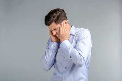 Photo of Young man suffering from headache on grey background