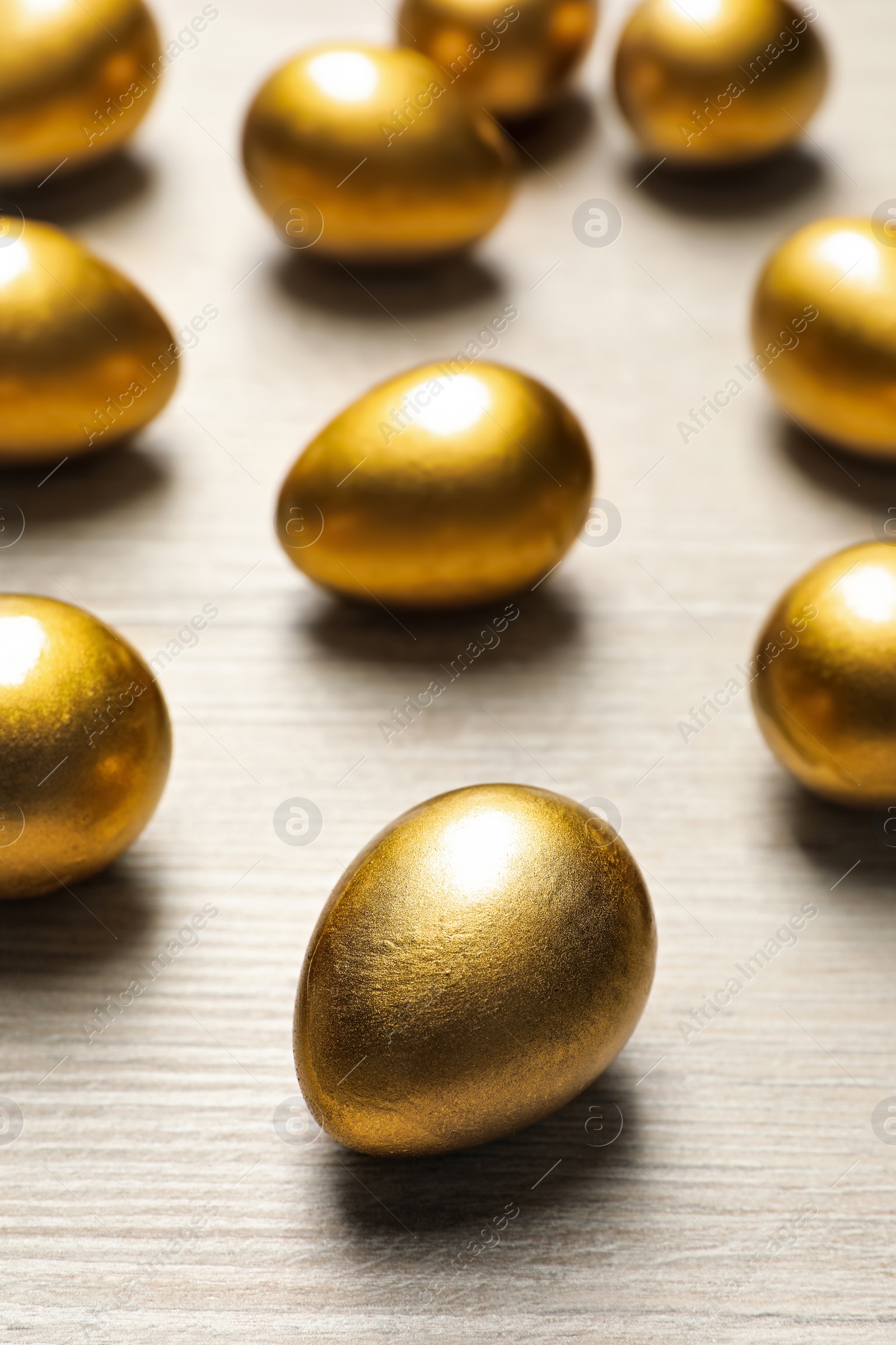 Photo of Many golden eggs on white wooden table