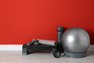 Photo of Different sports equipment near red wall in gym. Space for text