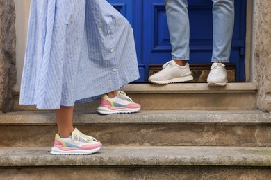 Photo of Woman and man wearing stylish sneakers on stairs outdoors closeup