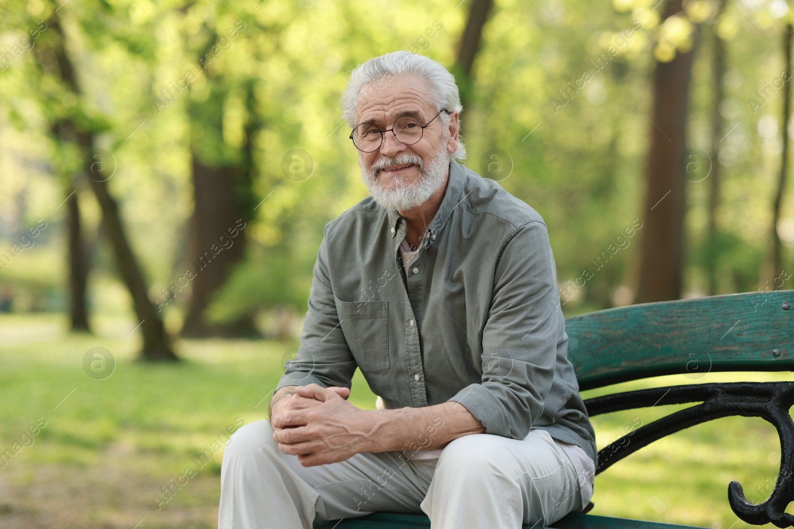 Photo of Portrait of happy grandpa with glasses on bench in park