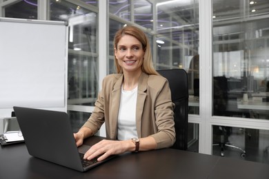 Photo of Woman working on laptop at black desk in office
