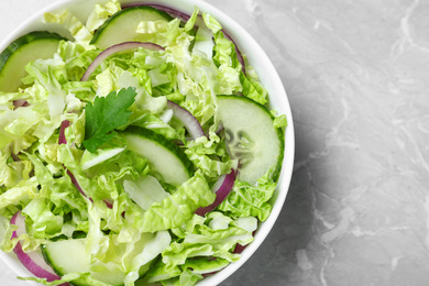 Photo of Tasty salad with cabbage and cucumbers on light grey marble table, top view