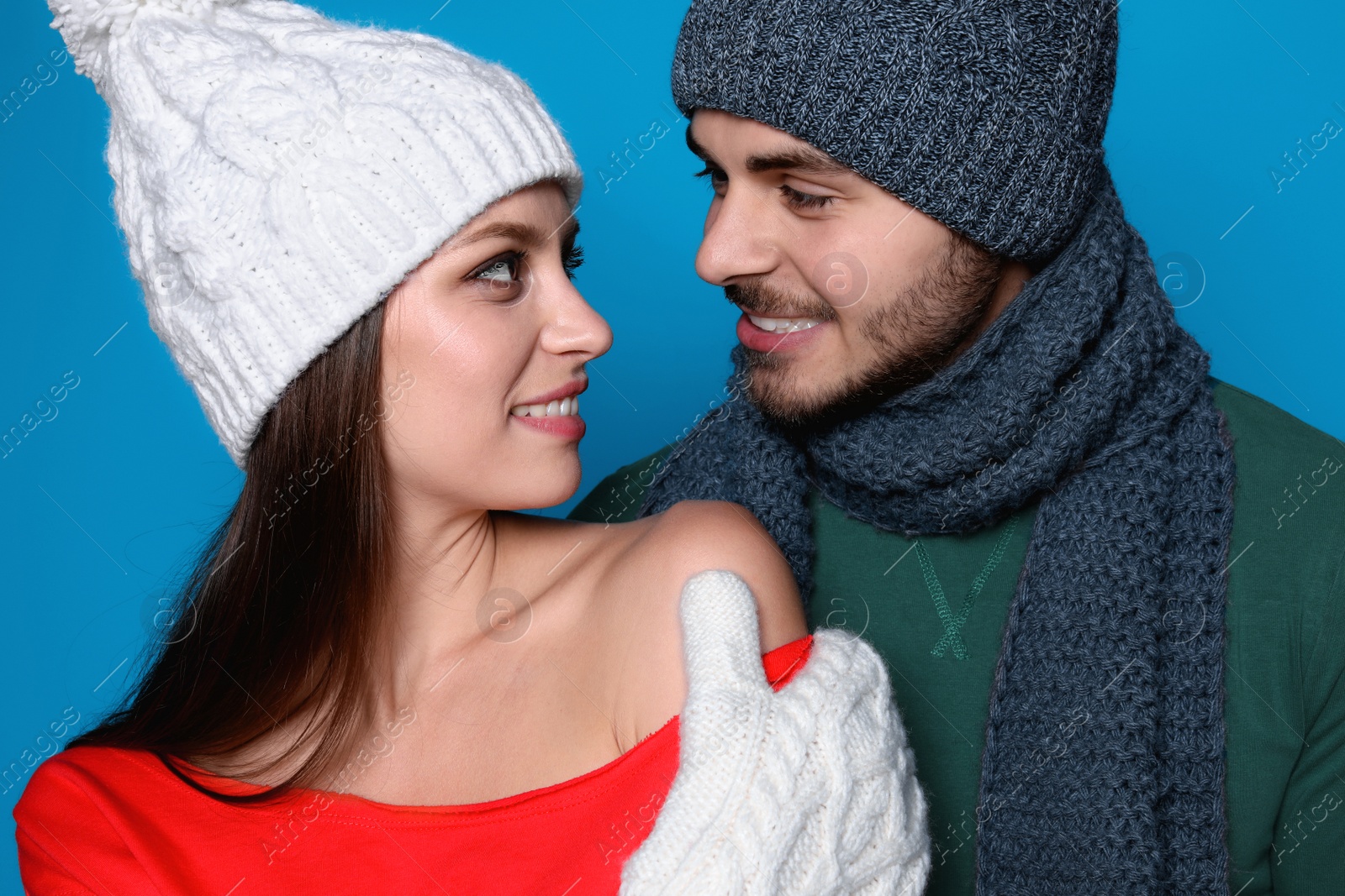 Photo of Young couple in warm clothes on color background. Christmas celebration