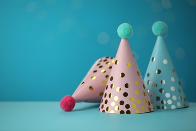 Beautiful party hats on light blue background, space for text