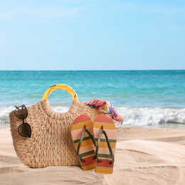 Bag with accessories on sunny ocean beach, space for text. Summer vacation
