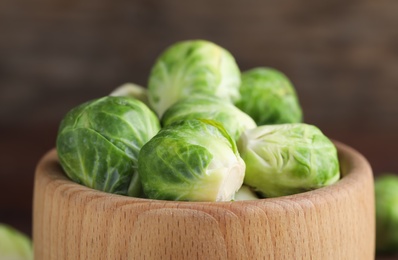 Photo of Fresh Brussels sprouts in wooden bowl, closeup