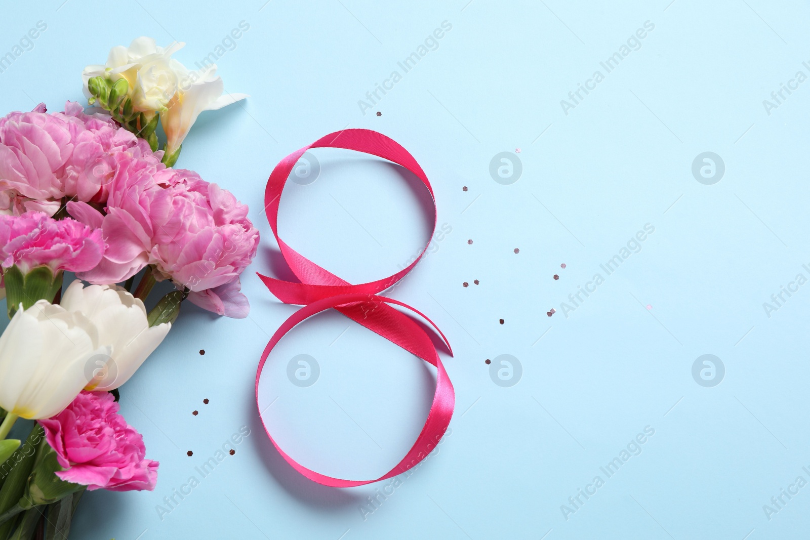 Photo of 8th of March greeting card design with pink ribbon, beautiful flowers and space for text on light blue background, flat lay. International Women's day