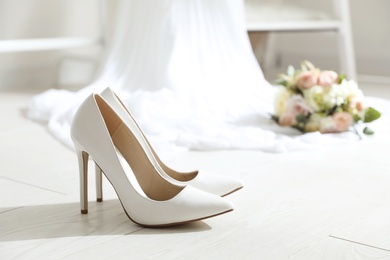 Pair of wedding high heel shoes on white wooden floor indoors
