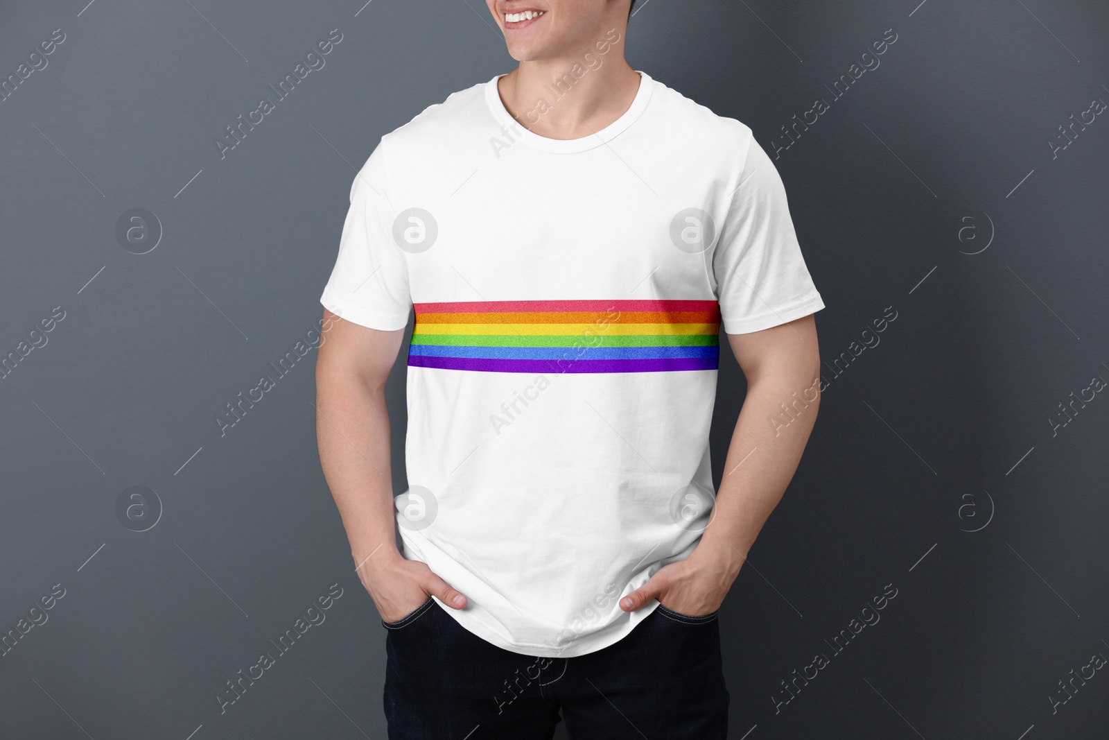 Image of Young man wearing white t-shirt with image of LGBT pride flag on grey background