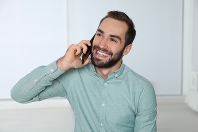 Photo of Young man laughing while talking on phone indoors