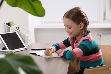 Photo of Girl erasing mistake in her homework at wooden table in room