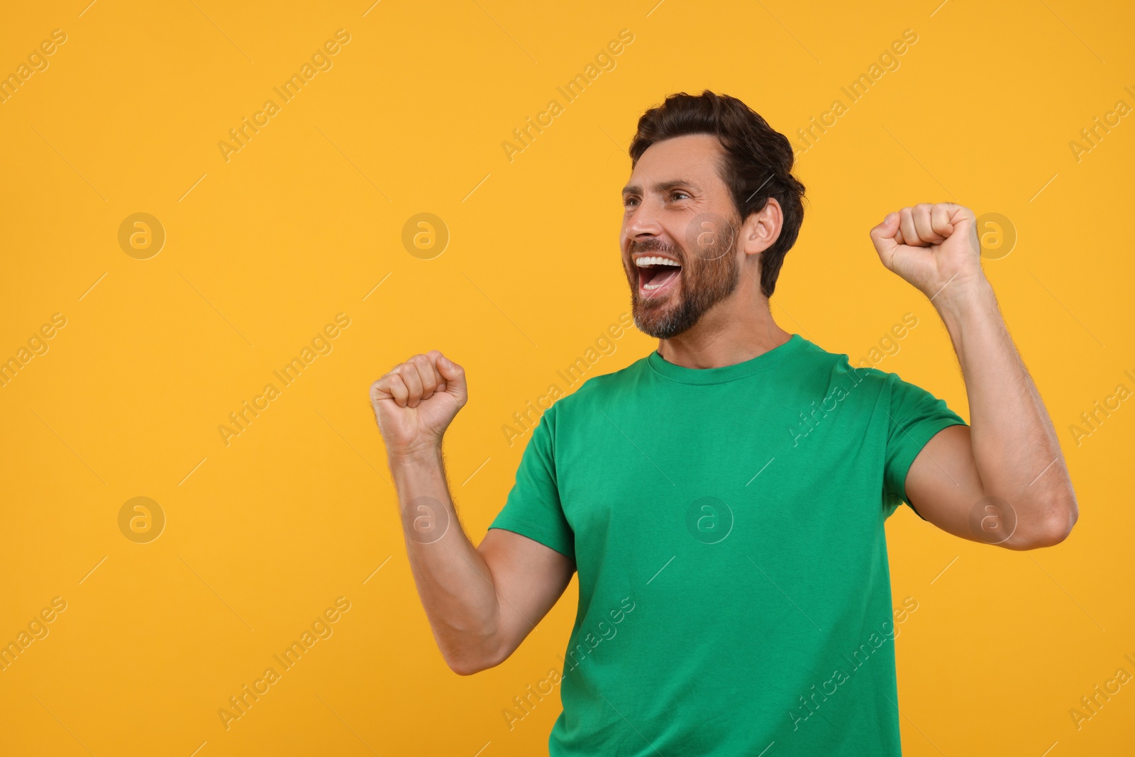 Photo of Emotional sports fan celebrating on orange background, space for text