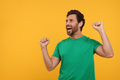 Photo of Emotional sports fan celebrating on orange background, space for text