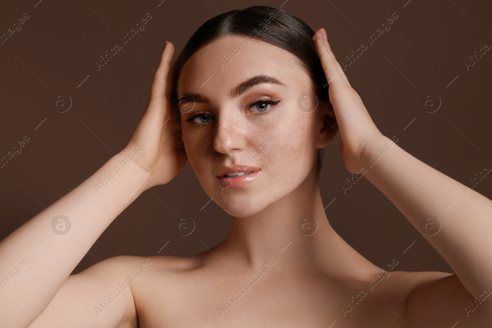 Photo of Portrait of beautiful woman with fake freckles on brown background