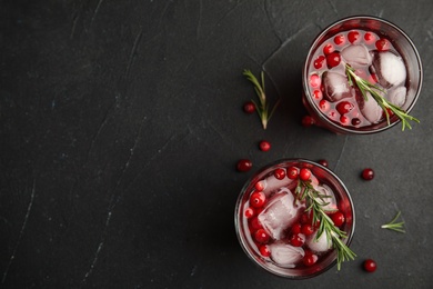 Tasty refreshing cranberry cocktail with rosemary on black table, flat lay. Space for text