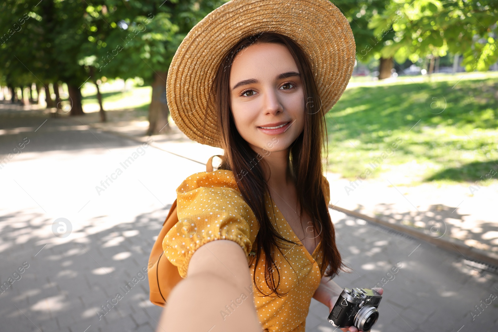 Photo of Travel blogger with vintage camera takIng selfie outdoors