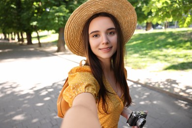 Travel blogger with vintage camera takIng selfie outdoors