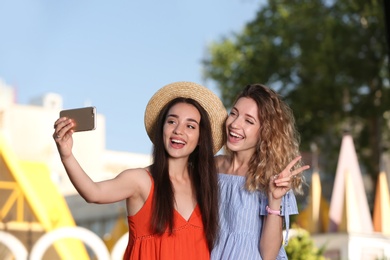 Photo of Happy young women taking selfie outdoors on sunny day