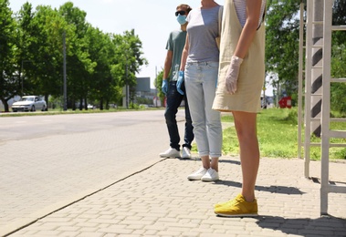 Photo of People keeping social distance in line at bus stop. Coronavirus pandemic