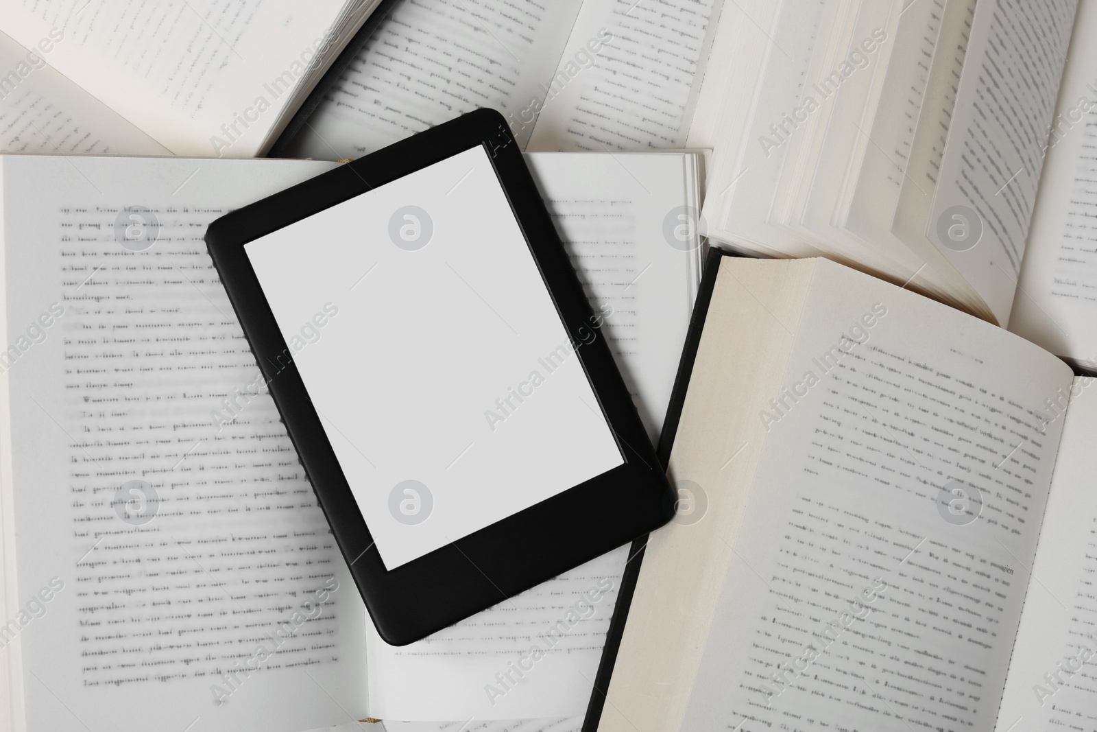 Photo of Portable e-book reader on different open books, top view