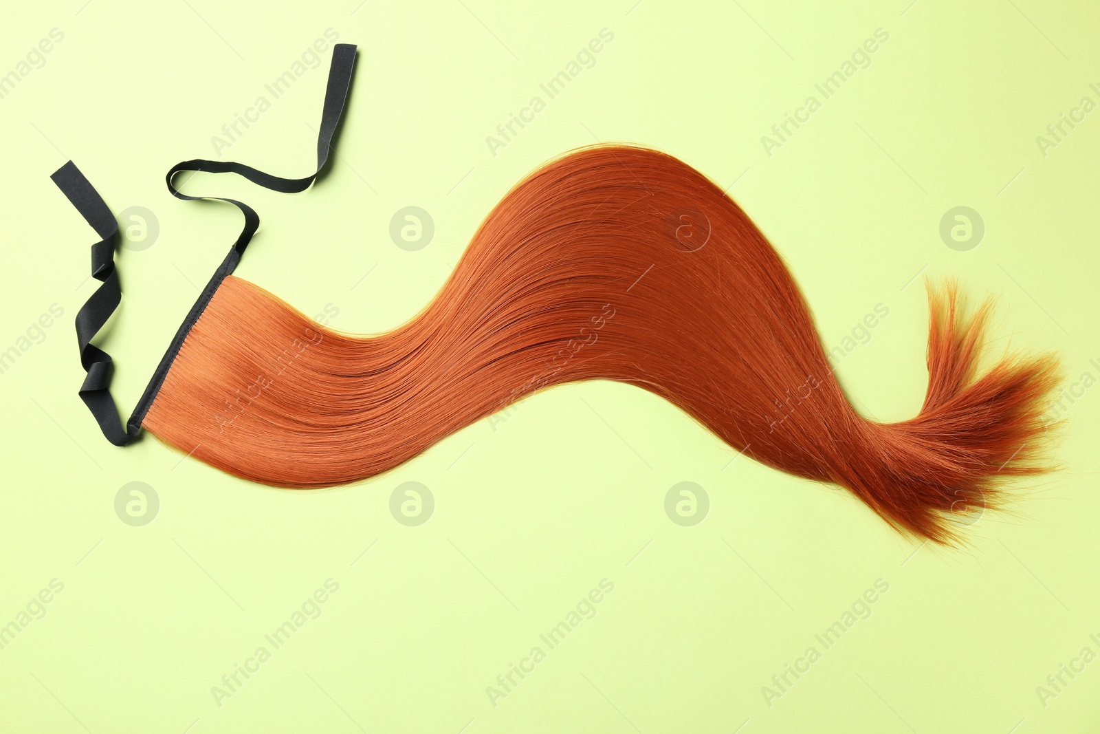Photo of Lock of straight red hair on color background, top view