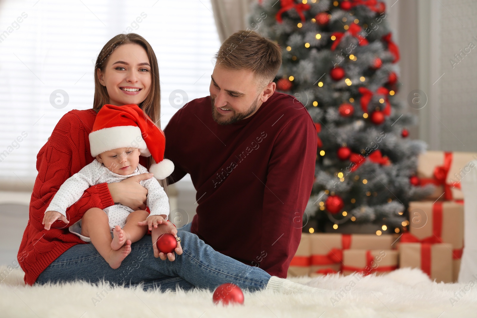 Photo of Happy family with cute baby in room decorated for Christmas holiday