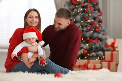 Happy family with cute baby in room decorated for Christmas holiday