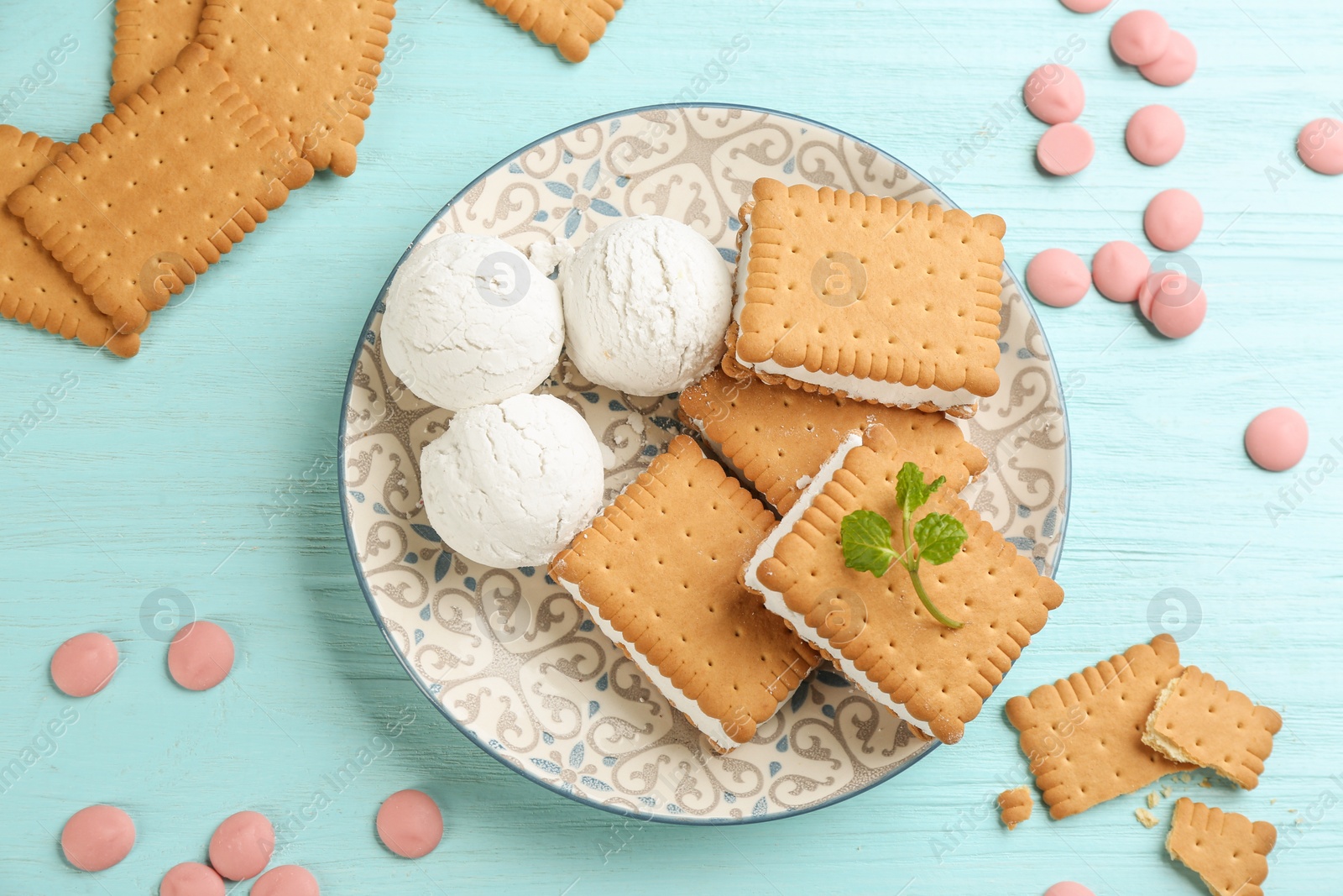 Photo of Sweet delicious ice cream cookie sandwiches on light blue wooden table, flat lay