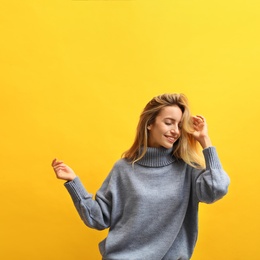 Beautiful young woman wearing knitted sweater on yellow background