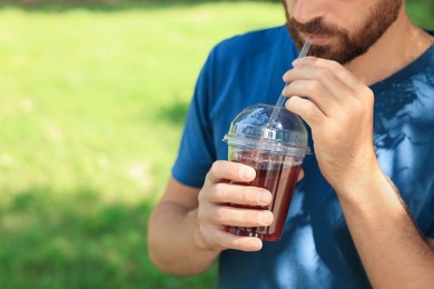 Photo of Man drinking delicious juice outdoors, closeup. Space for text