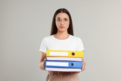Photo of Unhappy woman with folders on light gray background