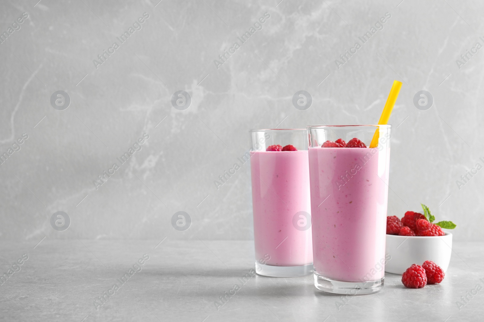 Photo of Glasses of tasty smoothie with raspberries on light table. Space for text