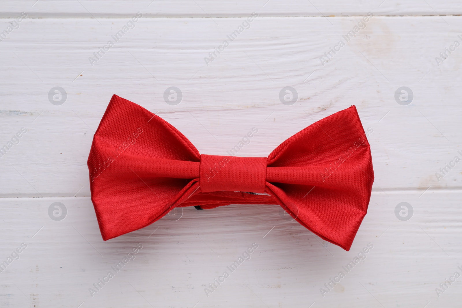 Photo of Stylish red bow tie on white wooden table, top view