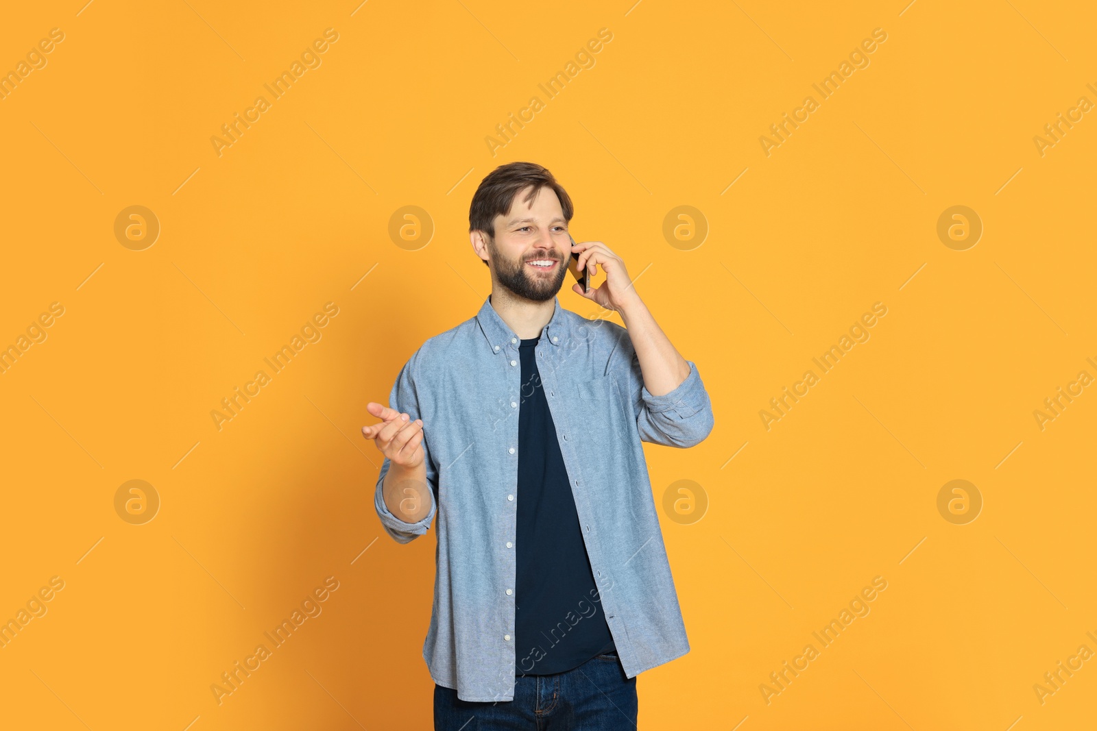 Photo of Man talking on smartphone against orange background