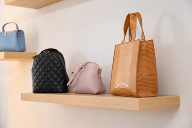 Photo of Stylish woman's bags on shelf in boutique