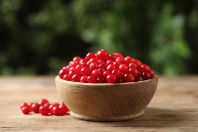 Photo of Ripe fresh cranberry in bowl on wooden table