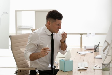 Photo of Ill businessman with nasal spray table in office