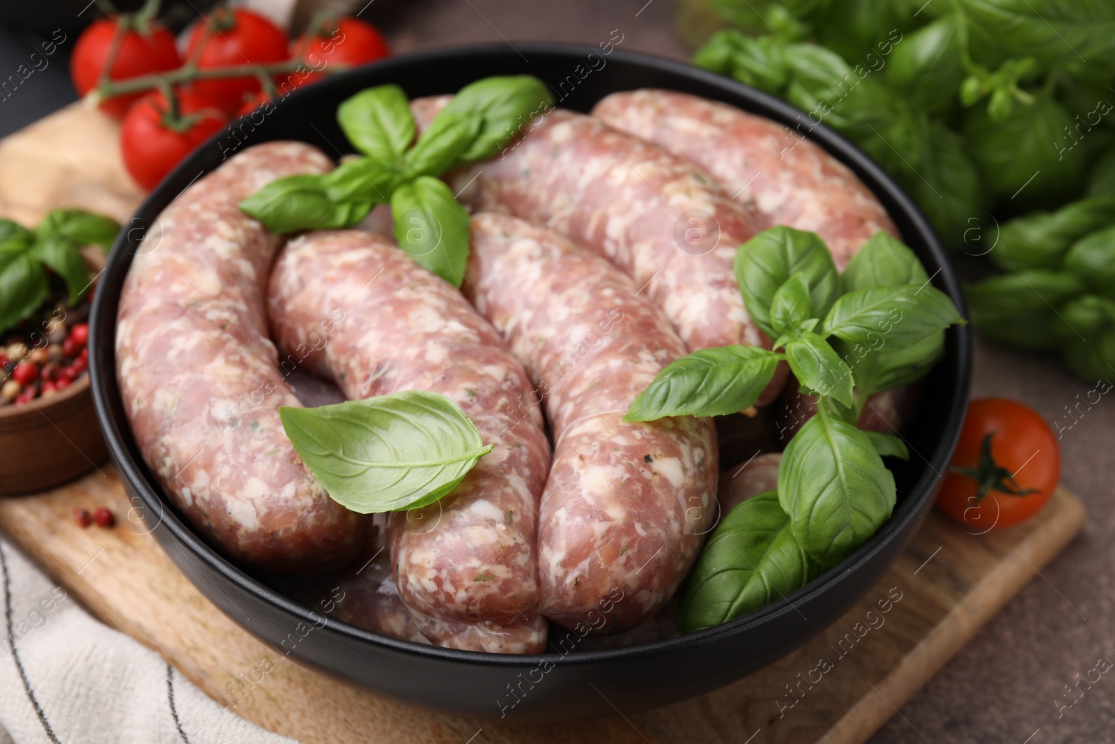 Photo of Raw homemade sausages and basil leaves on table, closeup
