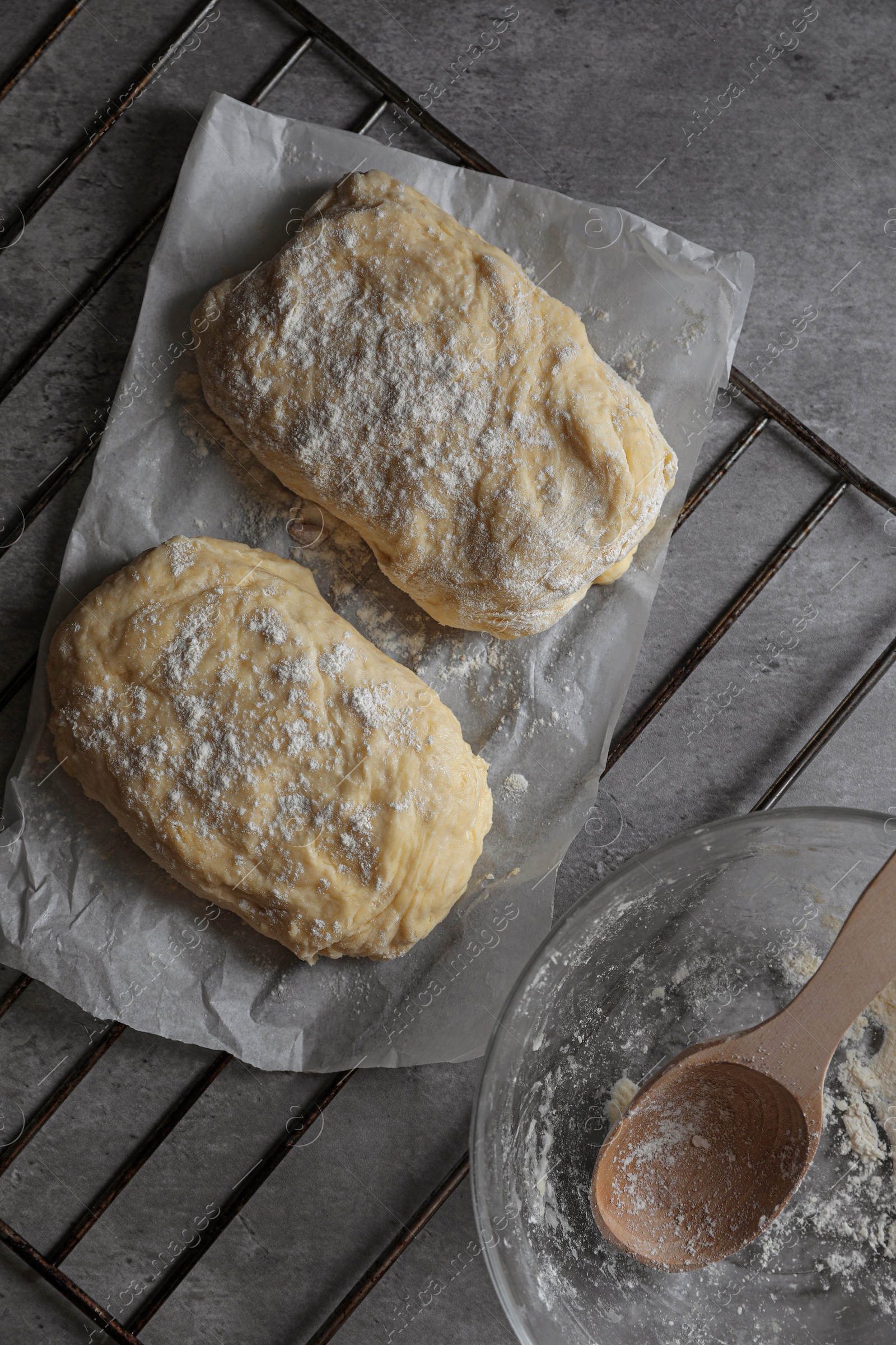 Photo of Raw dough for ciabatta and flour on grey table, flat lay