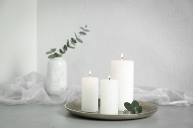 Burning candles on light grey stone table