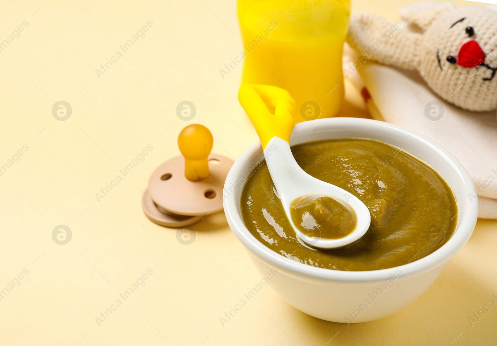 Photo of Bowl of healthy baby food on yellow background. Space for text