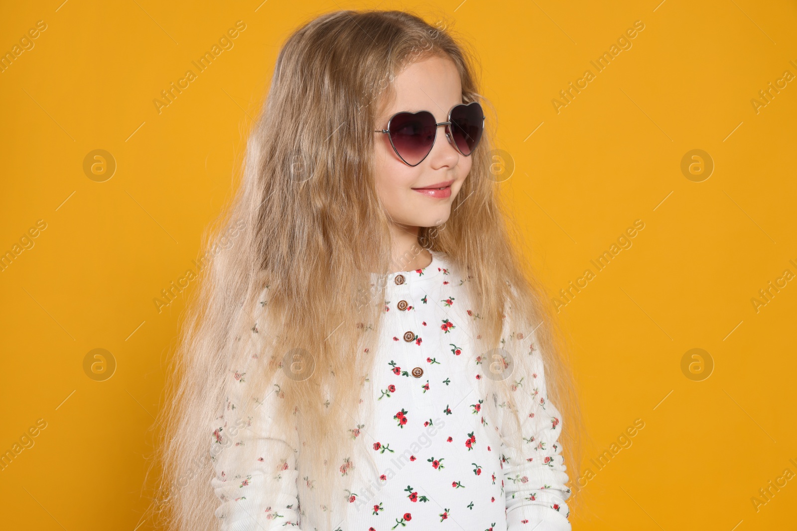 Photo of Girl wearing stylish sunglasses in shape of hearts on orange background