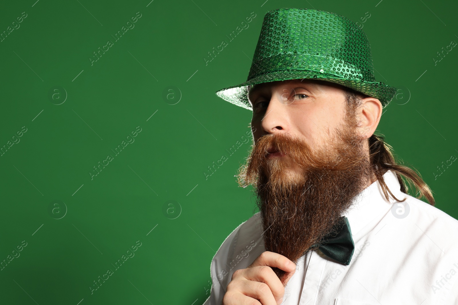 Photo of Bearded man in green hat on color background, space for text. St. Patrick's Day celebration