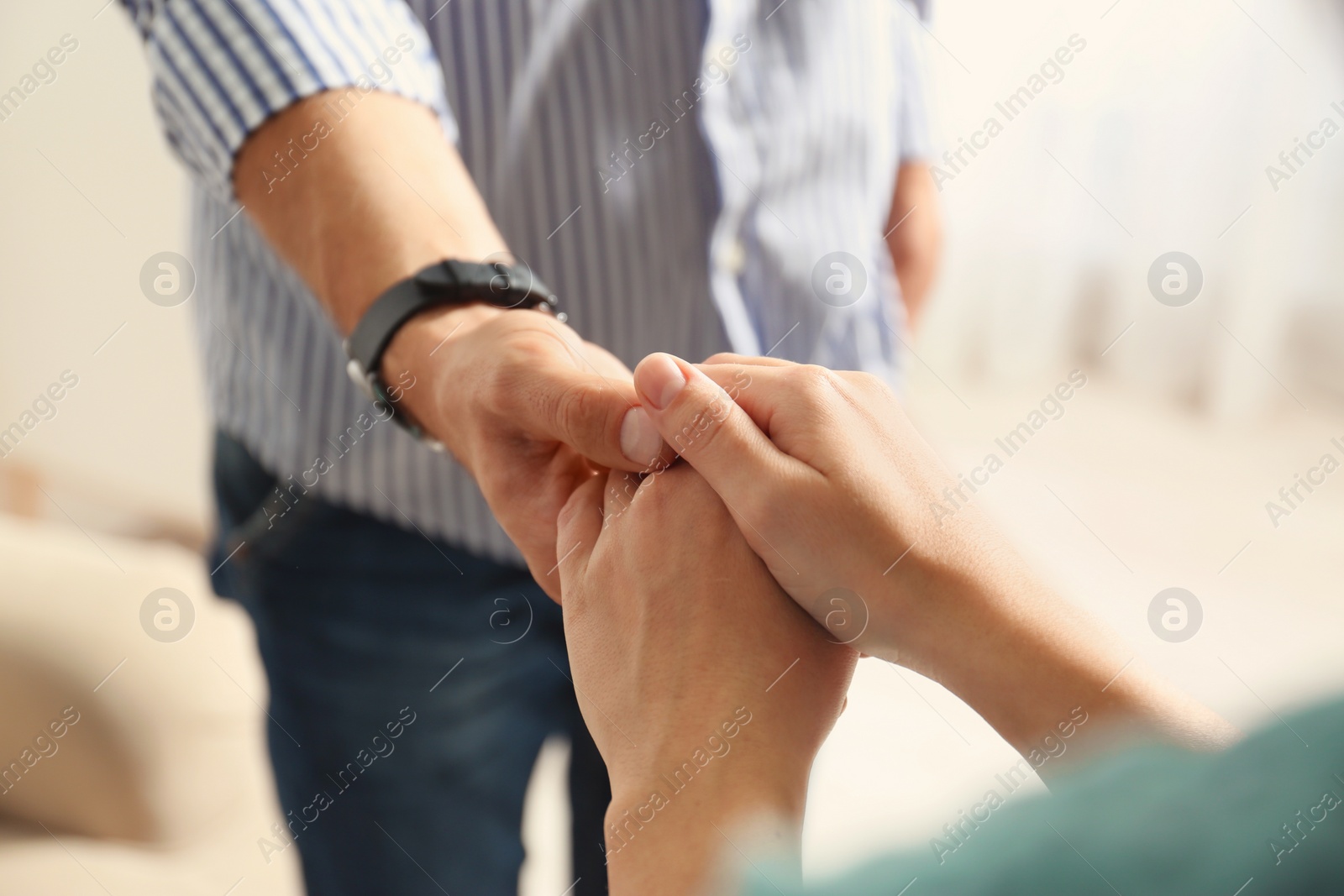 Photo of Man and woman holding hands on light background, closeup. Help and support concept